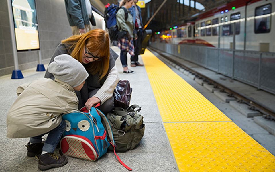 En kvinna och ett barn rotar bland väskor och ryggsätt på en tågperrong.